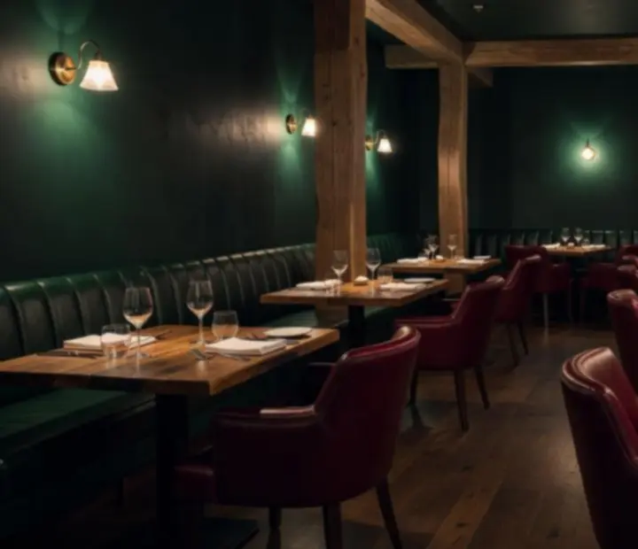 Hangulatos, meleg fényű, sötét smaragdzöld bistro belső, fa asztalokkal és bárpulttal